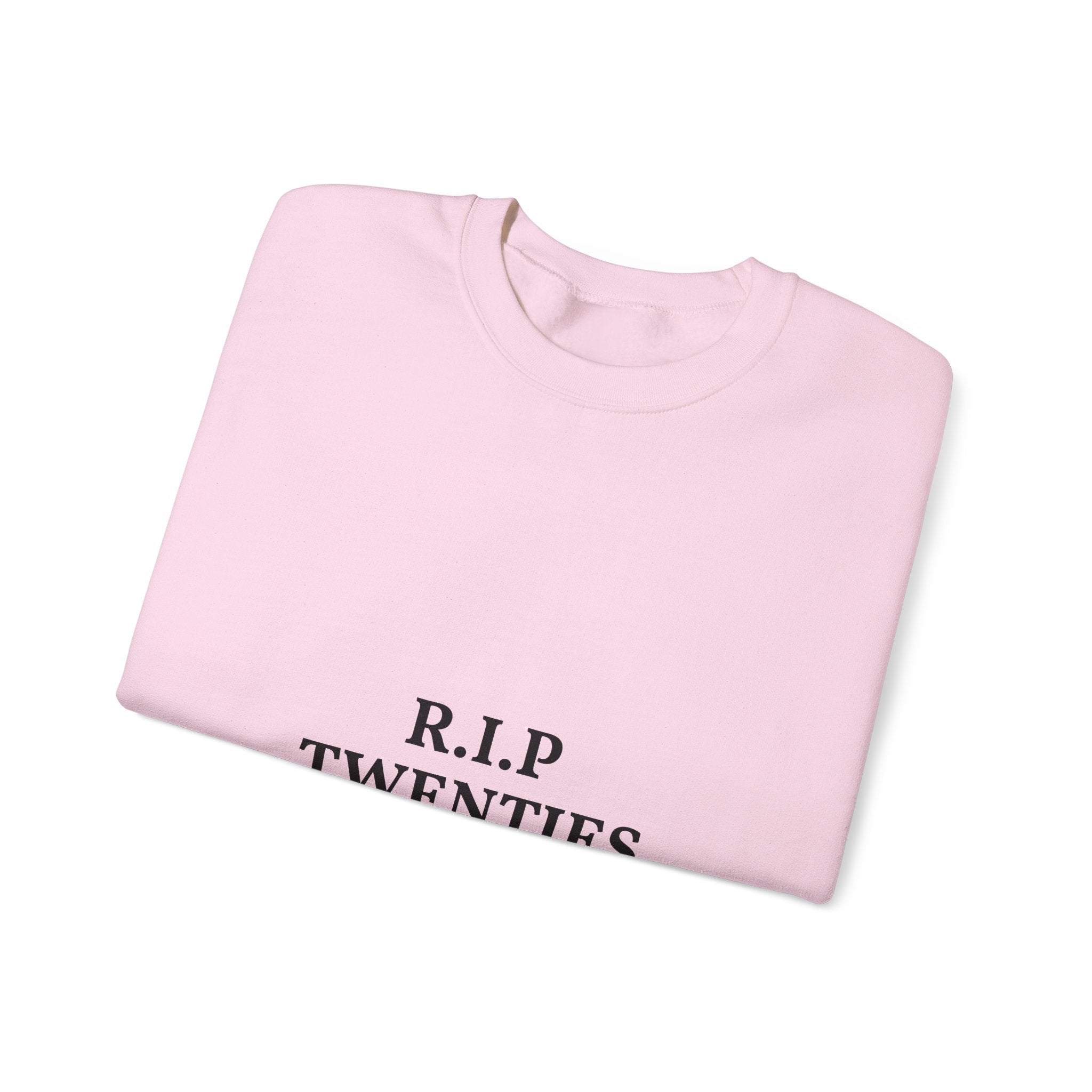 Folded pink sweatshirt with 'R.I.P. TWENTIES' text on a white background